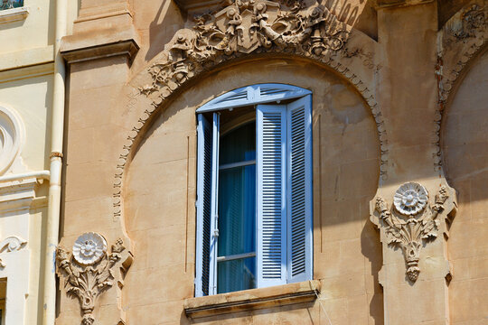 Open blue wooden shutters on an arched window with carved stone ornaments, Cannes, French Riviera