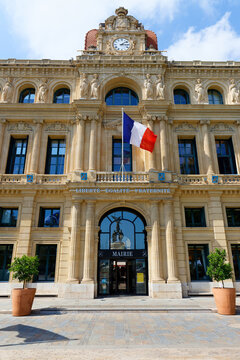Wide view of Cannes City Hall facade with flags and orange trees in terracotta pots, French Riviera