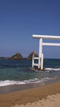 Sakurai Futamigaura shrine white Torii gate with Meoto Iwa Couple Stones, Married Couple Rocks with Shimenawa rope, Itoshima, Fukuoka prefecture, Japan, Kyushu island, landscape in a sunny day