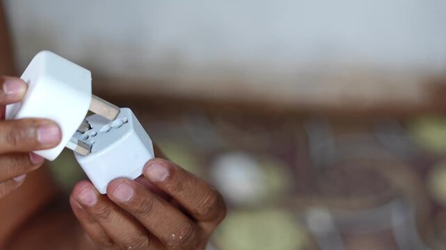 Person connecting international universal travel adapter to a power plug for global electricity compatibility