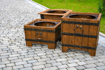 Empty decorative flower stands shaped as chests with wrought iron handles on paved walkway, urban landscaping concept © Dmitrii Labrador