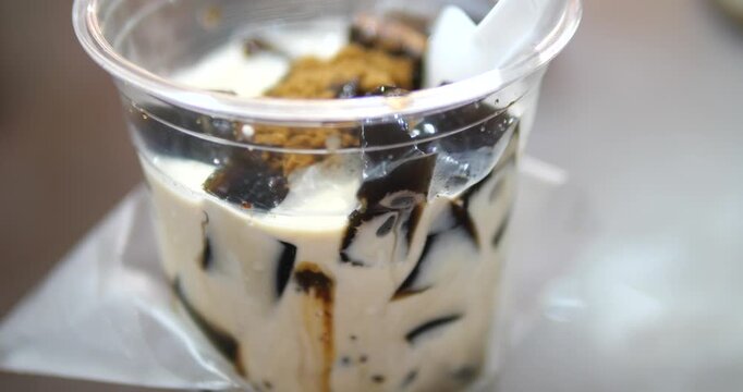 Close up of black grass jelly with fresh milk topped with brown sugar in plastic cup