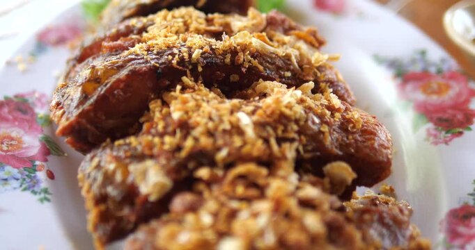 Close up of crispy fried fish topped with golden garlic on floral plate