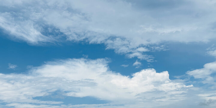 Soft white clouds drift across a clear azure-blue sky, airy natural backdrop for banners, wallpapers, travel designs, and atmospheric visual compositions.

