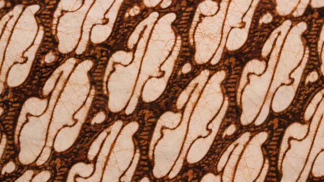 Traditional Indonesian Parang batik fabric pattern close up background, brown and cream textile design with intricate ethnic motifs and wax-resist dyeing details.
