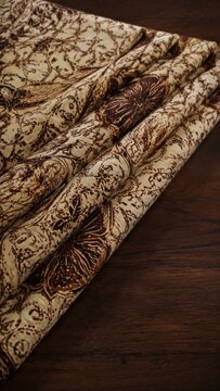 Traditional Indonesian Parang batik fabric pattern close up background, brown and cream textile design with intricate ethnic motifs and wax-resist dyeing details.