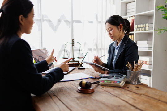 Asian lawyers consulting in a law office, discussing legal advice for clients, working on documents, representing justice, and providing professional attorney services