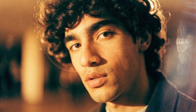 Grainy 35mm film portrait of a man, warm amber color grading, natural lens flare, subtle film grain, vintage aesthetics.   