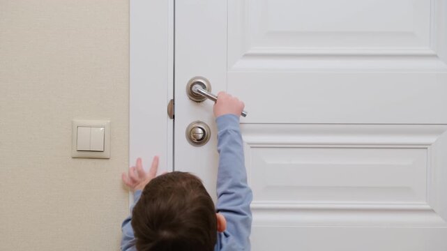 Child touching door frame in house. Little boy reaching to wall and door handle. Safety at home, childhood curiosity and exploration of indoor environment. Daily life activity concept.