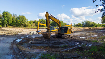 Yellow excavators level the construction site before building begins. © yaviki