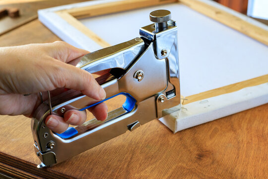 Hand Stapling Canvas Edge to Wooden Stretcher Frame with Metal Tacker. Art Mounting Concept