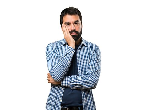 A bearded man wearing a plaid shirt looking thoughtful with his hand on face