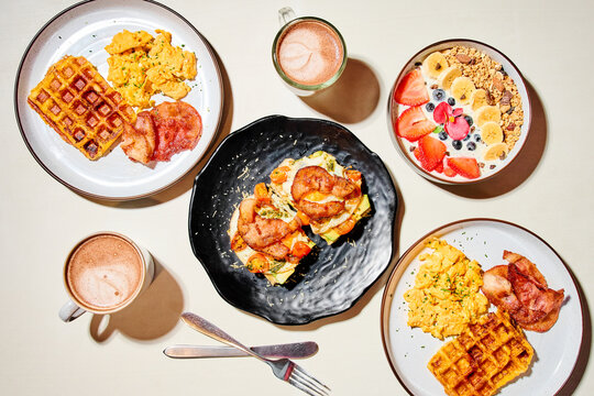 Breakfast spread featuring waffles, scrambled eggs and bacon