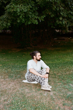 Man Sits on Grass in a Park During Daytime