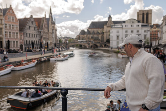 Man Tourist Looking at Scenic Canal and Boats from Korenlei in Ghent