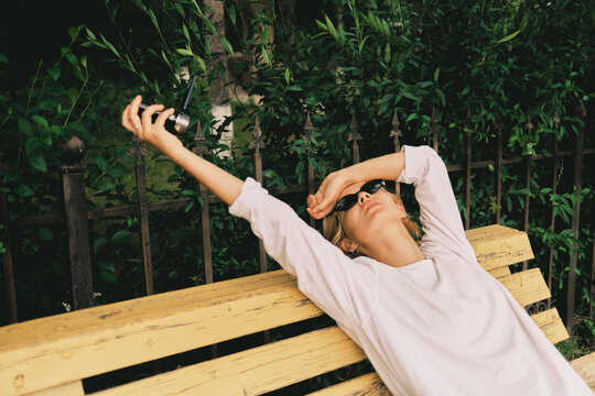 Woman relaxing on a bench in a green area with sunglasses