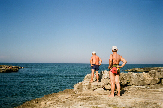 Senior Couple Standing by the Sea with Hands on Hips