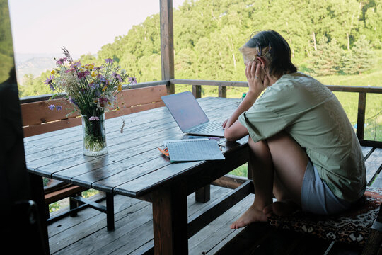 Girl studies Korean in a wooden cabin surrounded by nature