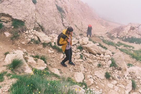 Hikers walk through rocky terrain in foggy conditions