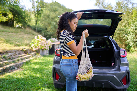 Woman loading groceries into car trunk after shopping