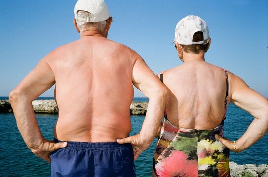 Senior Couple Standing by the Sea with Hands on Hips