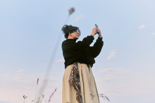 Woman taking a picture in an open field during sunset