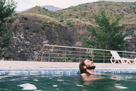 Man enjoying a moment by the pool near rocky hills