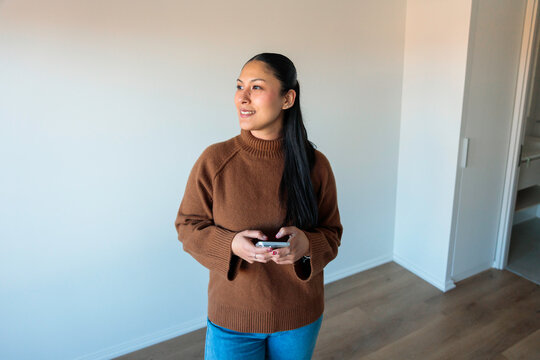 Latina woman holding phone while looking aside
