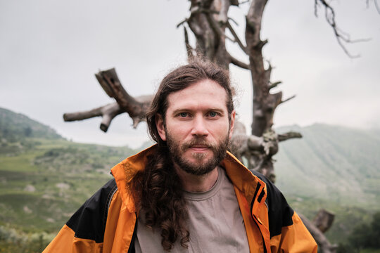 Man stands with tree in background on mountain during day