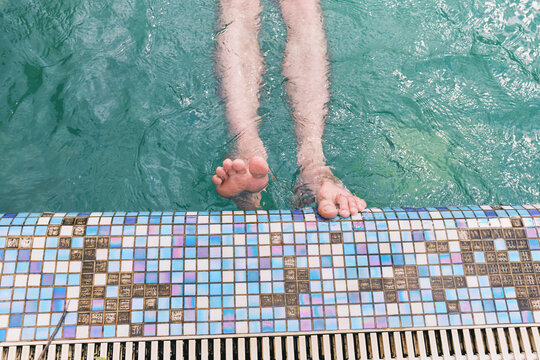 Feet in water by the pool during sunny day