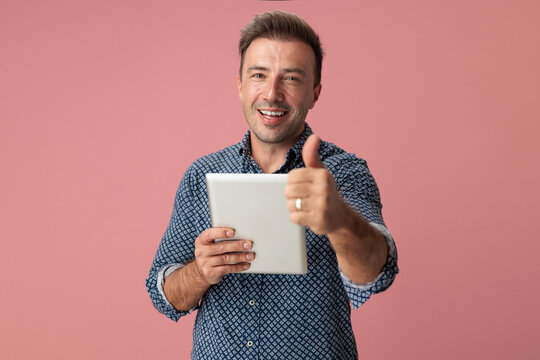 Happy man holding digital tablet and gesturing thumbs up