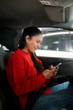 Young woman checking smartphone in car