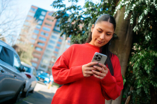 Latina woman checking mobile outdoors