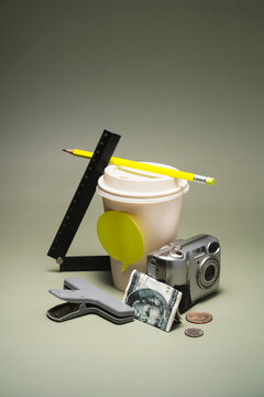 Lo-fi Stack of disposable cup, camera, money, clamp, ruler and pencil