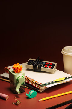 Stack of stationery with a retro game console on dark red background