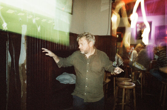 Man throwing darts in a pub with light streaks