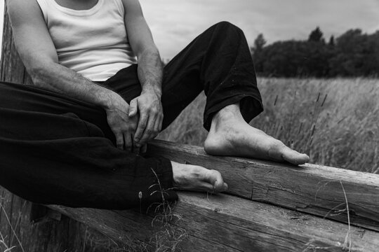 Calmness Candid Man Sitting on a Wooden Fence in Nature Field