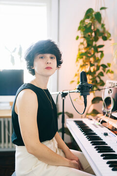 Woman creating music in home studio recording vocals