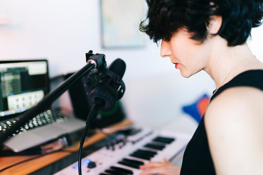 Woman playing keyboard and recording music in home studio