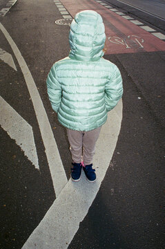 Child in green jacket standing on urban street