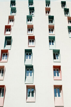 Rows of green and pink window frames on pale facade