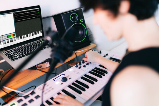 Musician creating music in home studio with laptop