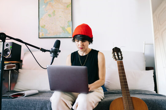 Woman creating music content using laptop and microphone