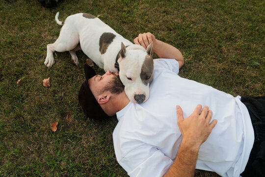 Man Lying On Grass With Dog Relaxing in City Park