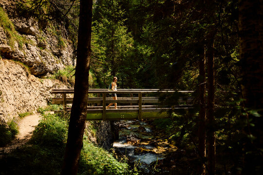 Woman crosses a wooden bridge in the mountain
