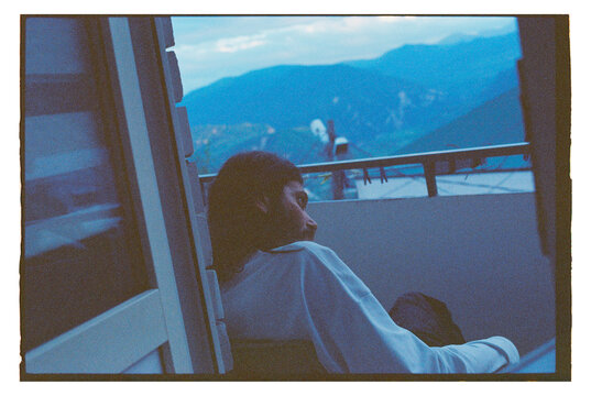 Person sits on balcony overlooking mountain view at dusk