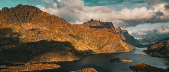 Vertical aerial view of a majestic fjord surrounded by golden autumn mountains in Norway with copy space in sky © Quality by Simon