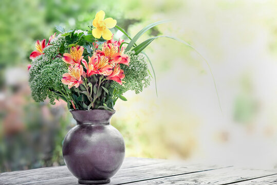 bouquet of beautiful flowers orange, red and yellow Alstroemeria Peruvian lily  in a vase on a table in garden