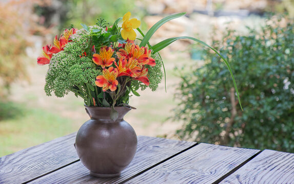 bouquet of beautiful flowers orange, red and yellow Alstroemeria Peruvian lily  in a vase on a table in garden