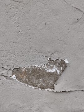 Close up of damaged concrete wall with large section of peeling paint revealing raw texture